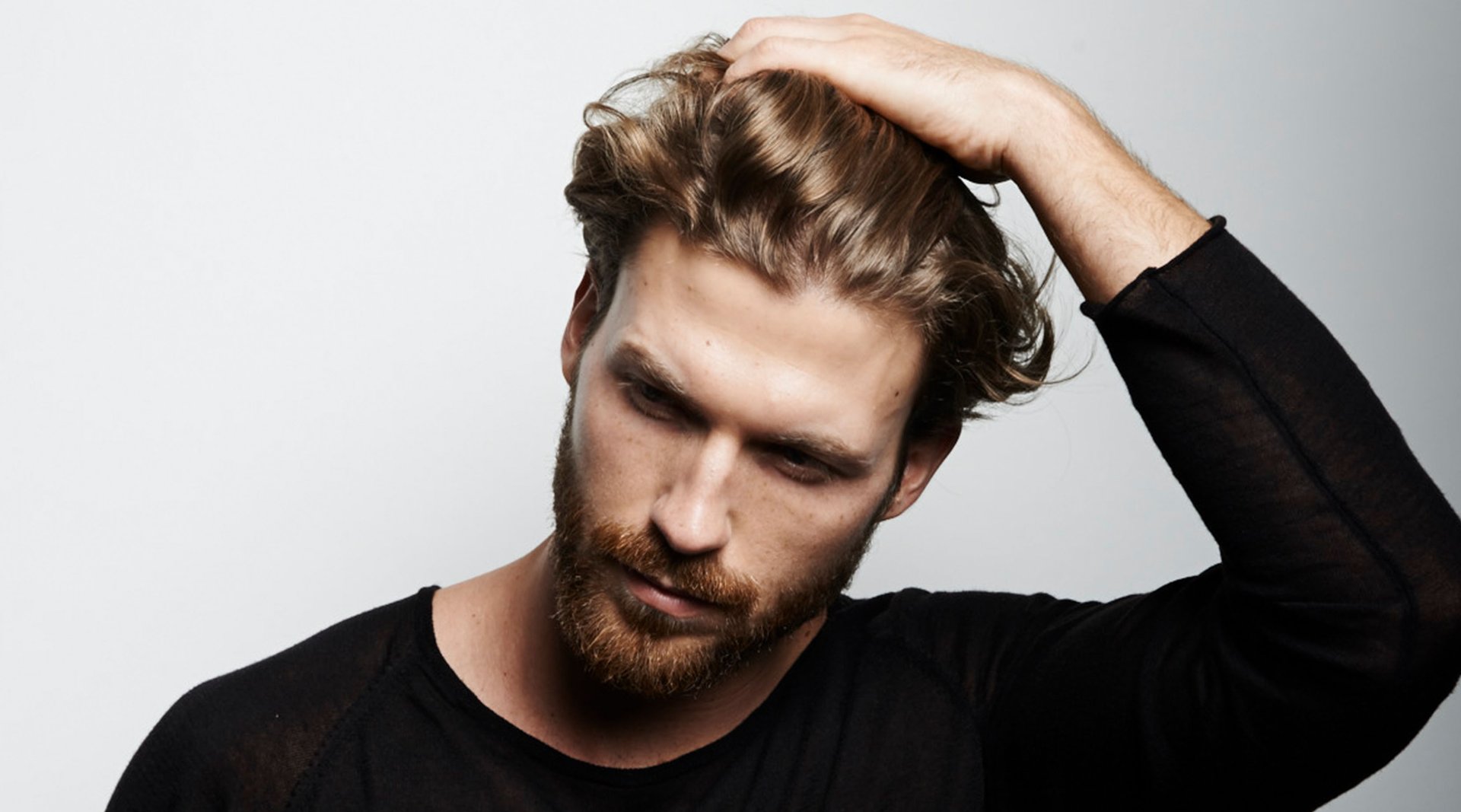 Mann fährt sich mit der Hand durch seine Haare